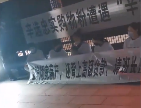多名受害者手拉横幅聚集在辛选直播基地门口